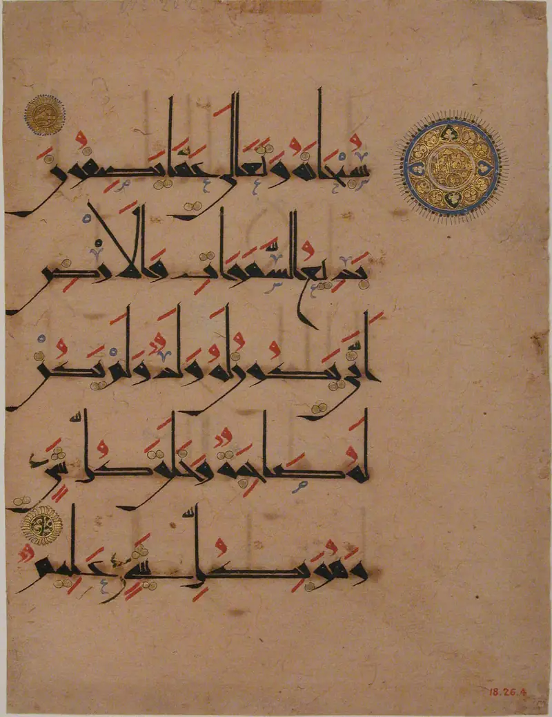 Folio de Coran manuscrit : cinq lignes d’écriture arabe noire à hampes très hautes, vocalisées en rouge, avec un médaillon doré marquant la fin d’un verset.
